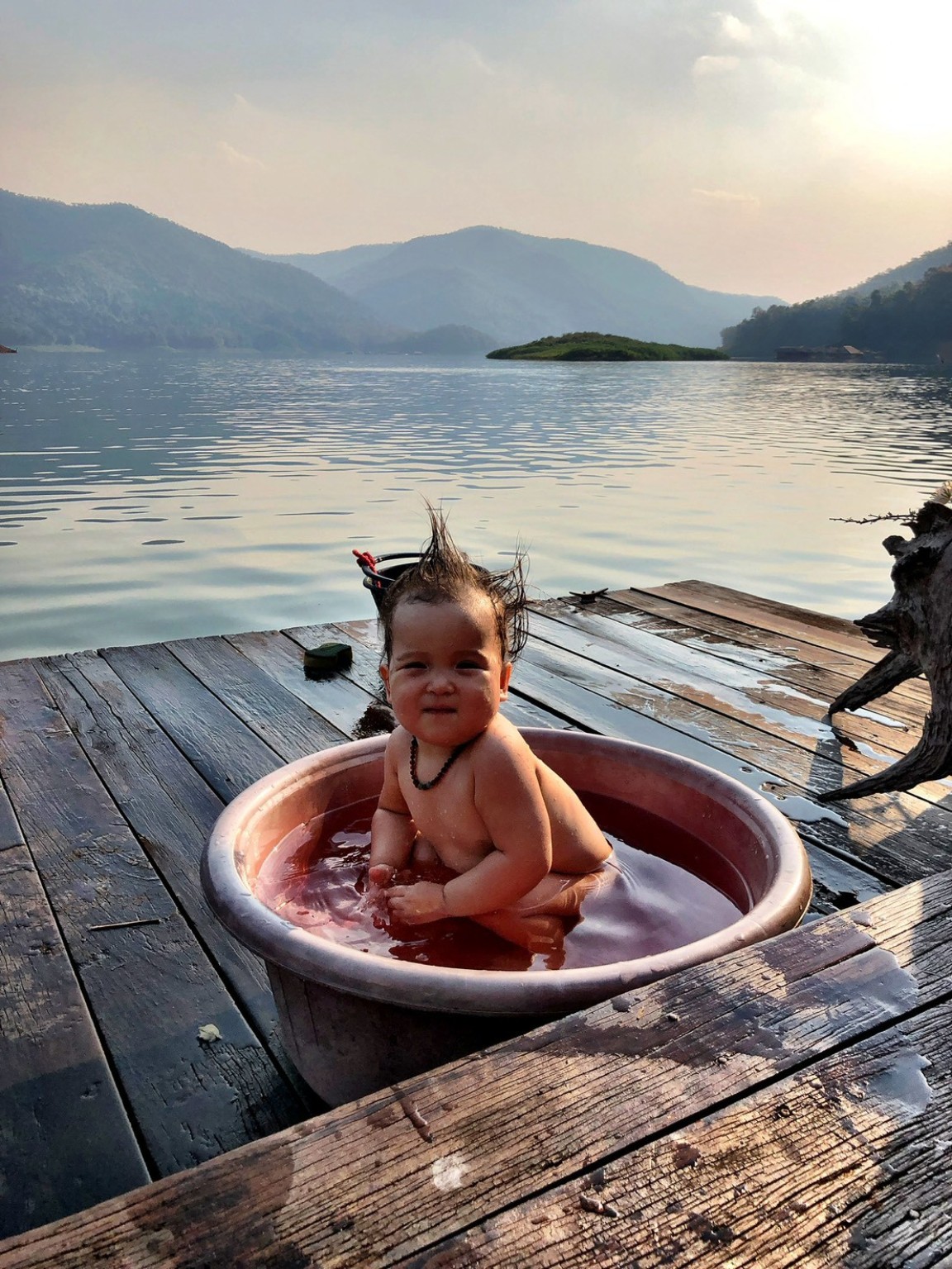 湖畔のたらいで水に触れる小さな子ども